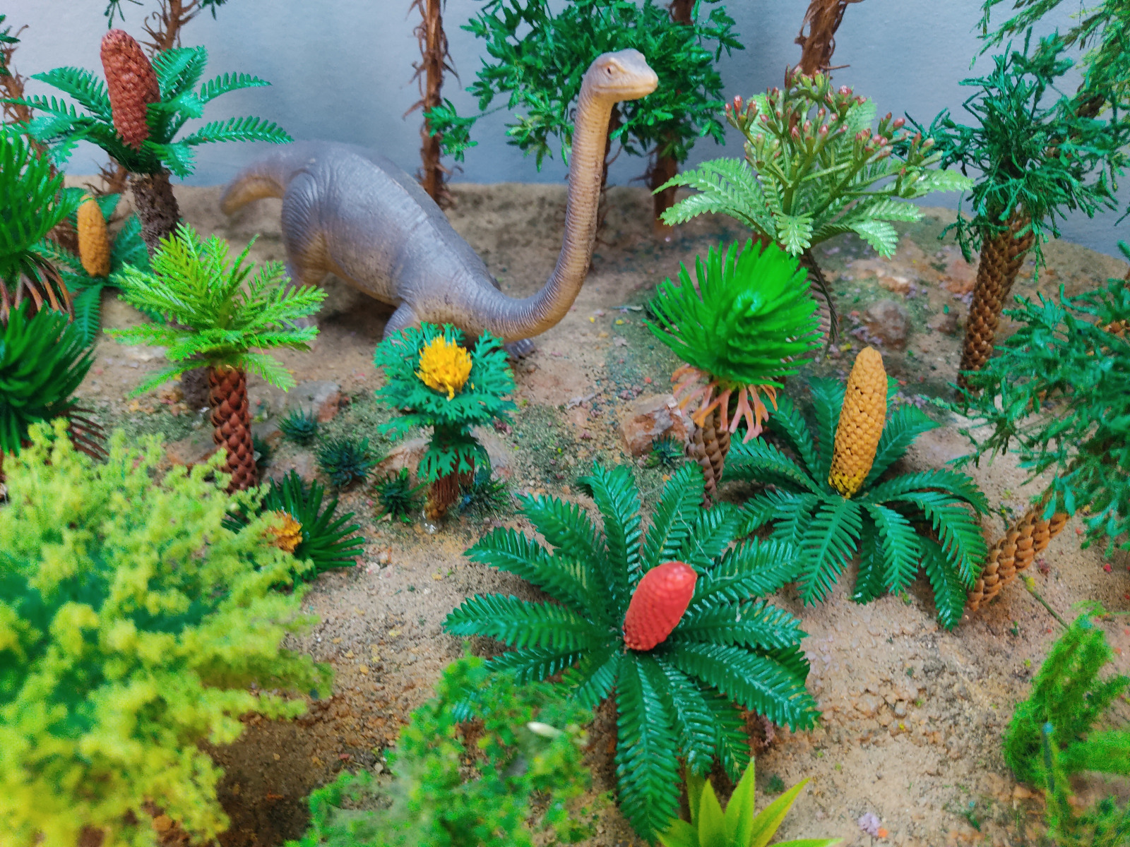 Saurópodo entre cícadas y coníferas prehistóricas a escala en una maqueta de Nature Center